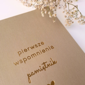 Detal beżowego albumu pamiątkowego dla dziecka Pierwsze wspomnienia – złote tłoczenie i faktura płótna
